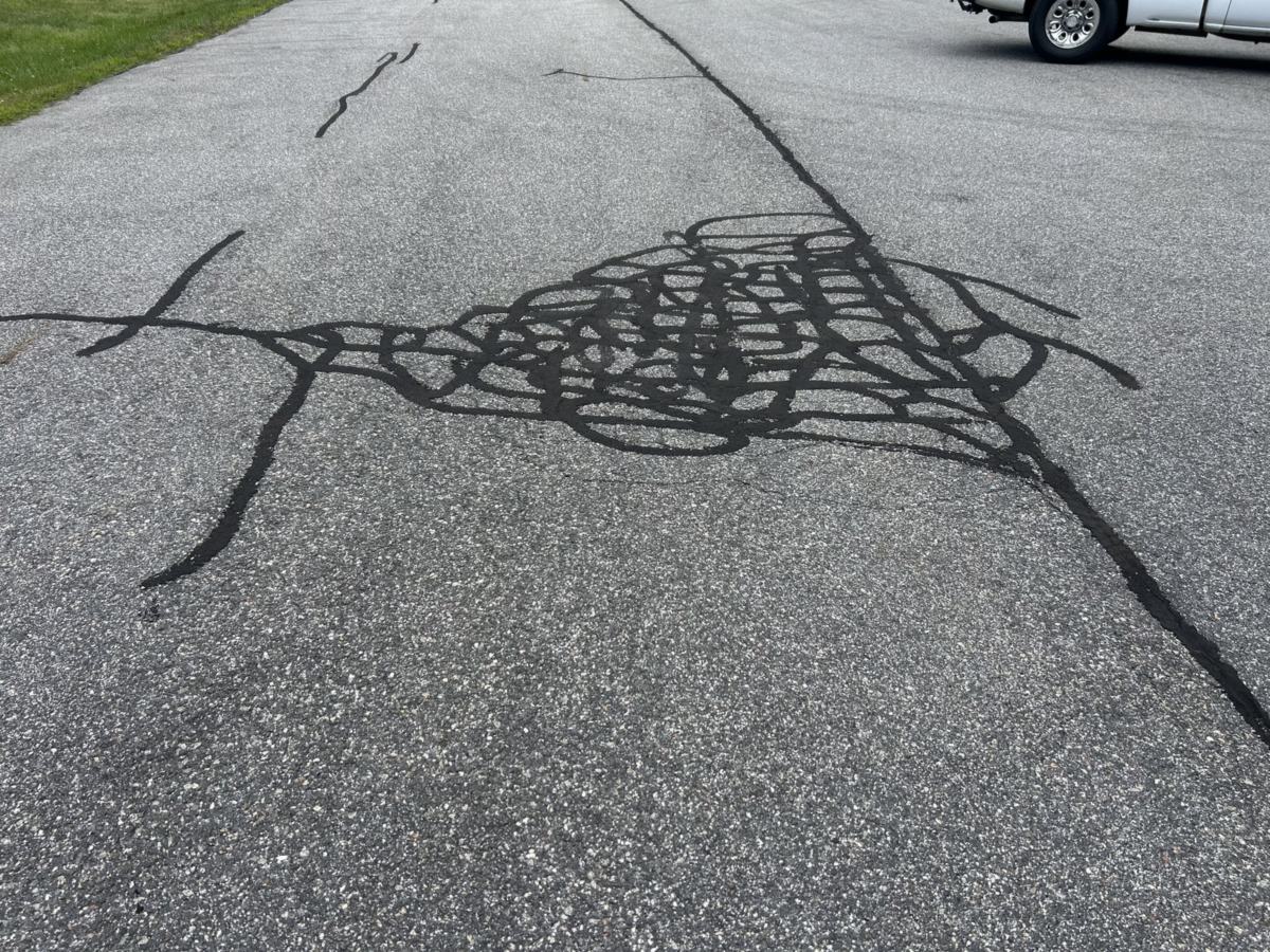Hot-pour crack sealant filling a network of cracks in an asphalt lot in Southern Maine