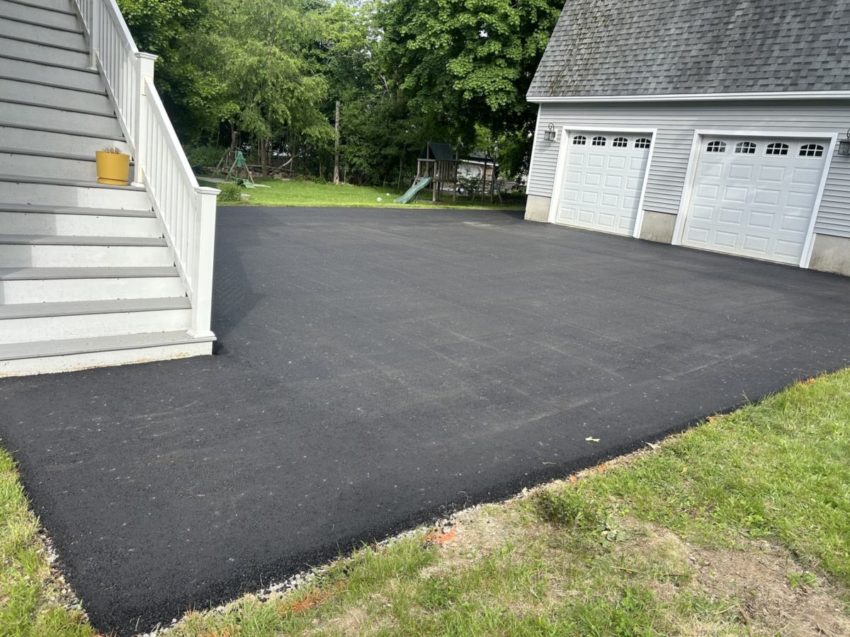 Freshly paved wide asphalt driveway in front of a two-car garage in Portland, Maine