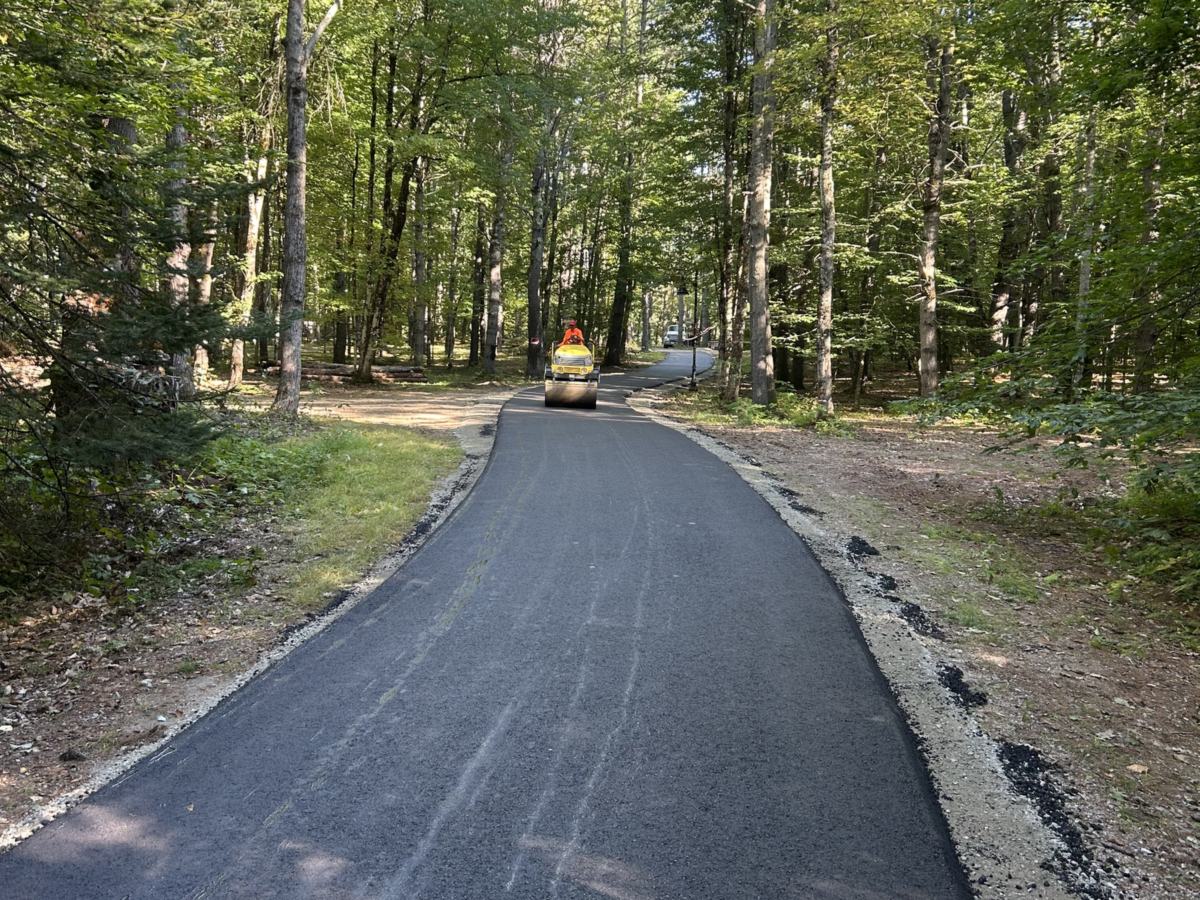 Roller compacting a newly paved private road through the woods in Windham, Maine