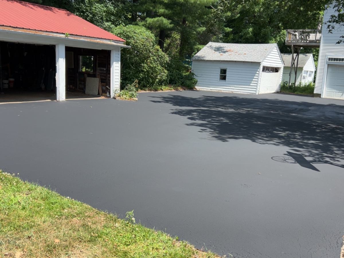 Freshly sealcoated residential driveway with a deep black finish in Southern Maine